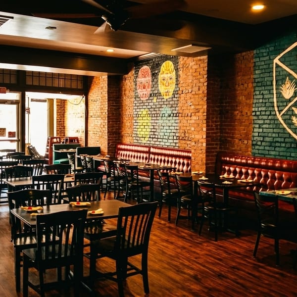 Spacious restaurant dining room with brick walls, red booths, dark tables, and a large butterfly window decal.