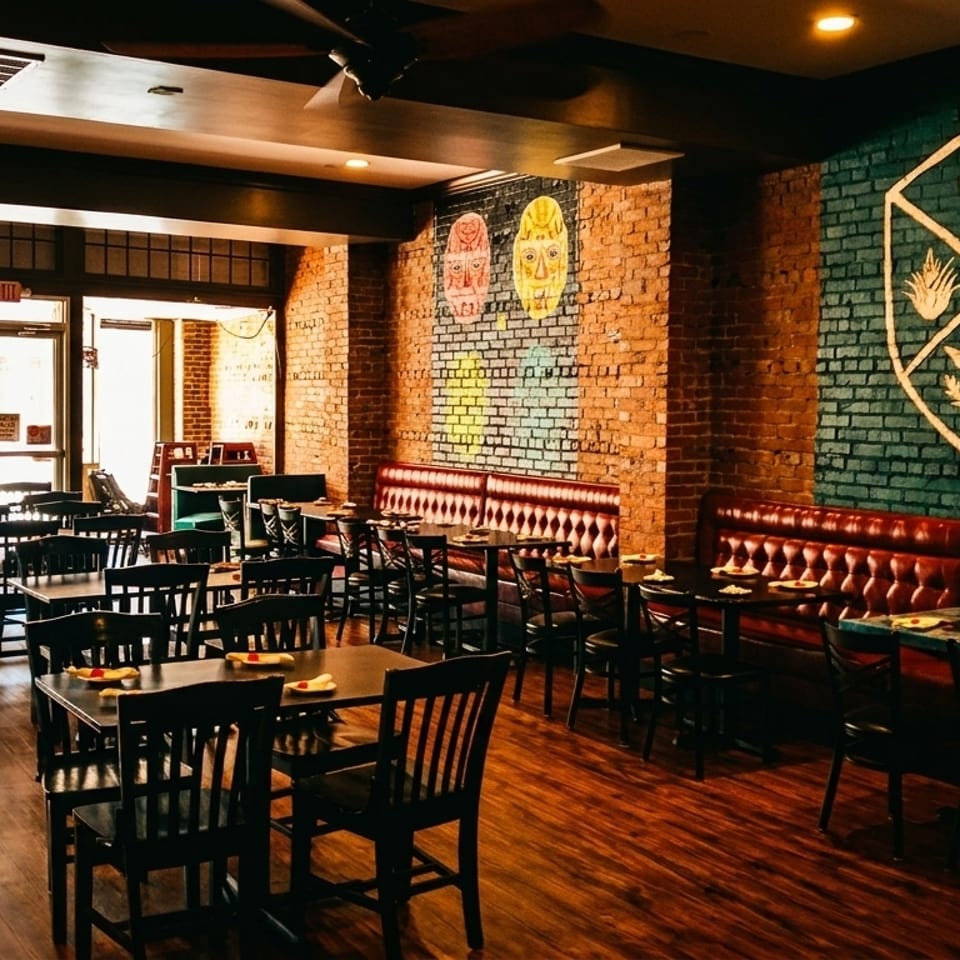 Spacious restaurant dining room with brick walls, red booths, dark tables, and a large butterfly window decal.