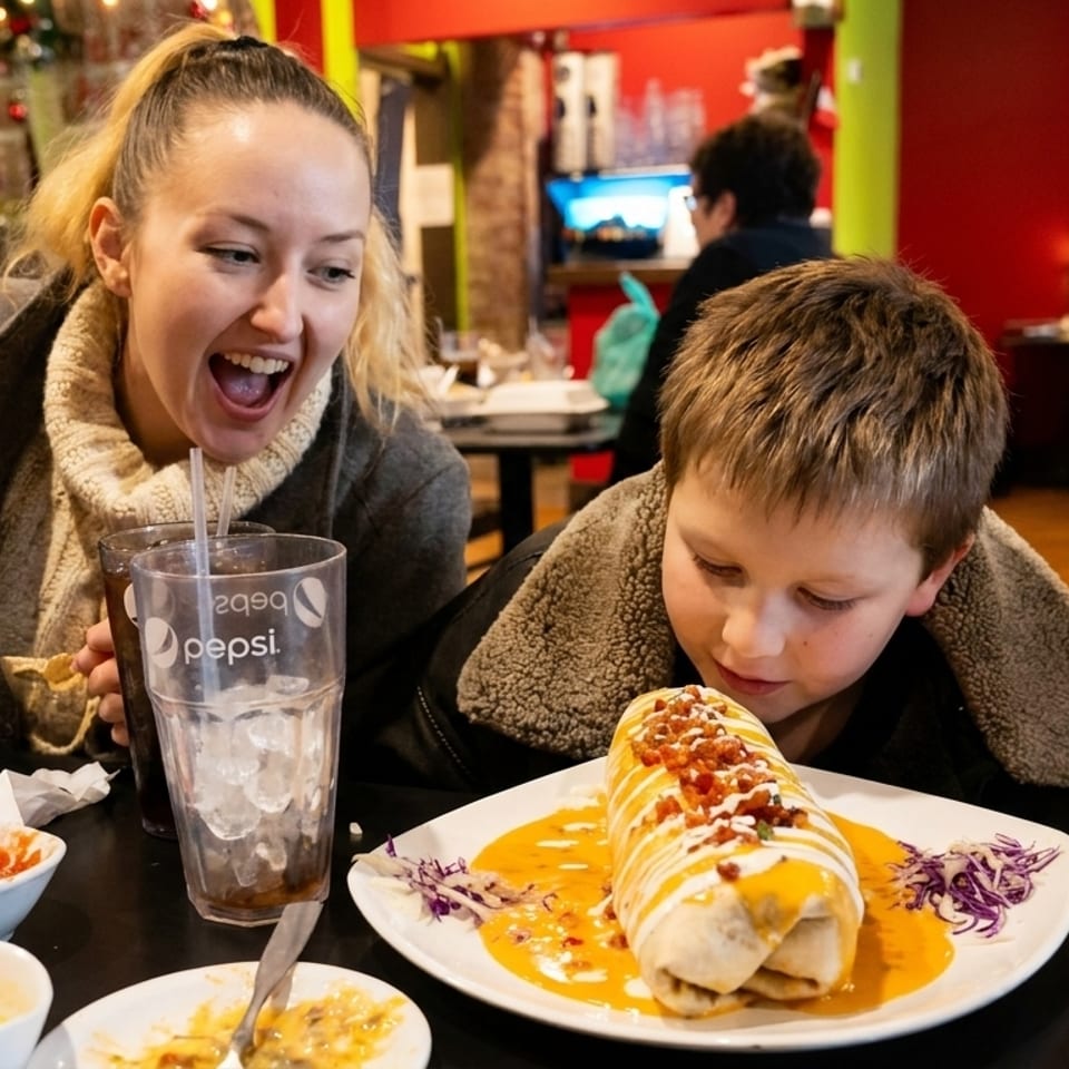 A woman and boy at a restaurant table, with the boy looking at a large burrito.